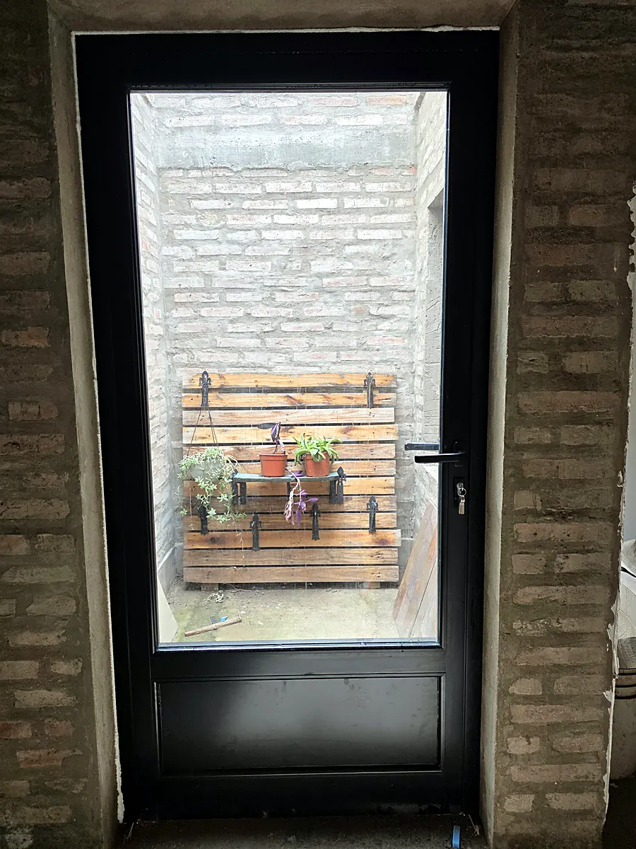Puerta de aluminio negro vidriada hacia un patio